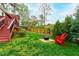 Spacious backyard with lush green grass, mature trees, fire pit, and red Adirondack chairs at 6819 Franklin Heights Rd, Cary, NC 27518