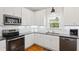 Well-lit kitchen features white cabinets, stainless steel appliances, dark countertops, and a window overlooking the yard at 6819 Franklin Heights Rd, Cary, NC 27518