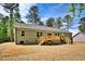 Backyard view of home with wooden deck, newly seeded yard and wooded backdrop at 7120 Guess Rd, Hillsborough, NC 27278