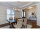 Elegant dining room with wood floors, white wainscoting, a modern light fixture, and dark wood door at 721 Shelley Rd, Raleigh, NC 27609