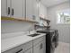 Modern laundry room features gray cabinets, a sink, wood shelves, and updated washer and dryer at 802 Knollwood Dr, Apex, NC 27502