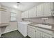 Functional laundry room features washer, dryer, sink, counter space, and ample storage cabinets for easy chore management at 803 Driftwood Dr, Gibsonville, NC 27249