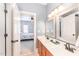 Bathroom with double vanity, light wood cabinets, mirrors, and doorway leading to bedroom with floral bedding at 944 Alden Bridge Dr, Cary, NC 27519