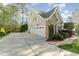 View of three-car garage and well-manicured landscaping surrounding this two-story home at 944 Alden Bridge Dr, Cary, NC 27519
