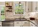 Well-lit kitchen features white cabinets, backsplash tiles, a stainless steel sink, and wooden shelves at 95 Torrington Ave, Franklinton, NC 27525