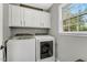 Bright laundry room features a washer, dryer, white cabinets, and a window for ventilation at 95 Torrington Ave, Franklinton, NC 27525
