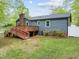 Exterior shot of the home features a deck with wooden stairs, landscaping, and mature trees at 1015 Castalia Dr, Cary, NC 27513