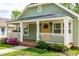 Cozy front porch with detailed trim, decorative lights, and a view of the lush front yard and garden at 1023 Kent St, Durham, NC 27707