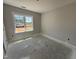 A bright bedroom with large window offers natural light and unfinished concrete floors at 107 Tee Dr, Selma, NC 27576