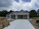 New home with gray siding, black roof, open garage, and concrete driveway at 107 Tee Dr, Selma, NC 27576