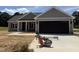New construction home showing a spacious two-car garage with gray siding and a well-manicured lawn at 107 Tee Dr, Selma, NC 27576