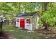 Backyard shed featuring red doors, green space, and a manicured lawn at 108 Braxberry Way, Holly Springs, NC 27540