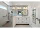 Bright bathroom featuring a dual vanity, walk-in shower, and neutral tile at 108 Braxberry Way, Holly Springs, NC 27540