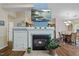 Living room featuring a cozy fireplace and TV, flowing into a dining area with hardwood floors at 108 Braxberry Way, Holly Springs, NC 27540