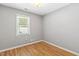 Neutral bedroom featuring gray walls, hardwood flooring, and a window at 12 Poppy Trl, Durham, NC 27713