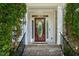 Inviting front entrance with an ornate glass door flanked by green shrubbery and brick steps with iron railings at 12808 Edsel Dr, Raleigh, NC 27613