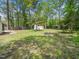Large, grassy backyard featuring mature trees, a storage shed and fire pit at 1312 Rothes Rd, Cary, NC 27511