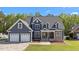 Charming blue two-story home with a well-manicured lawn, stone accents, and a three car garage at 133 Aleah Ct, Clayton, NC 27520