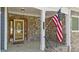 Inviting front porch with stone facade, decorative door, and American flag at 133 Aleah Ct, Clayton, NC 27520