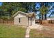 Tan storage shed with shingled roof and exterior door surrounded by a wooden fence at 140 Adams Pointe Ct Ct, Angier, NC 27501