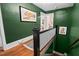 Hallway with hardwood floors and green painted walls, showcasing artwork and the staircase at 1403 Vickers Ave, Durham, NC 27707