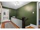 Hallway featuring hardwood floors and dark green walls, leading to the bathroom with white fixtures at 1403 Vickers Ave, Durham, NC 27707