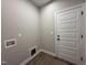 A well lit laundry room with white trim, a door to the exterior, and flooring that looks like wood at 152 Royal Ave, Selma, NC 27576
