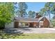View of the rear of a brick home, featuring a covered parking area and a fenced backyard at 1602 Lake Shore Dr, Dunn, NC 28334