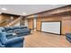Basement living area featuring plush sofas, wood paneling, wood-look floors, stairs, and a large projection screen at 1602 Lake Shore Dr, Dunn, NC 28334
