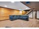 Finished basement featuring wood-look flooring, a large sectional sofa, and wood-paneled walls leading to the staircase at 1602 Lake Shore Dr, Dunn, NC 28334