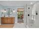 Bright bathroom showcasing a modern vanity, glass shower, round mirror, light blue walls, and walk out to porch at 1602 Lake Shore Dr, Dunn, NC 28334