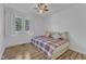 Sunny bedroom with a plaid bed, hardwood floors, and a bright window view at 1623 Alicary Ct, Cary, NC 27511