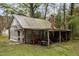 Exterior view of the cabin's porch, showcasing tools and a lawnmower, surrounded by lush greenery at 1823 E Geer St, Durham, NC 27704