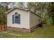 Side exterior view of a manufactured home, with blue shutters, and greenery at 1823 E Geer St, Durham, NC 27704