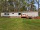 Spacious mobile home with a wooden deck, grill, and green lawn, perfect for outdoor living and entertainment at 1823 E Geer St, Durham, NC 27704