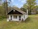 Small white building with a dark roof, windows, and a chimney on a lot of land with grass and trees at 1823 E Geer St, Durham, NC 27704