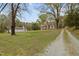Estate including a stone cottage, an additional small home, tall trees, and gravel driveway at 1823 E Geer St, Durham, NC 27704
