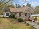 Charming stone home featuring a stone facade, brown roof, and small wooden deck and lush yard at 1823 E Geer St, Durham, NC 27704