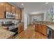 Well-lit kitchen with stainless steel appliances, granite counters, hardwood floors, and a view to dining area at 2002 Patapsco Dr, Apex, NC 27523