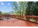 A wooden back deck with a stained red finish overlooks the yard and neighborhood pool at 211 Kurtner Ct, Morrisville, NC 27560