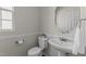 Half bathroom with a pedestal sink, toilet, and round mirror at 211 Kurtner Ct, Morrisville, NC 27560