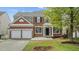 Two-story brick home featuring a two car garage and a well-manicured lawn with lovely landscaping at 211 Kurtner Ct, Morrisville, NC 27560