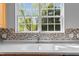 Close-up of kitchen sink and countertop with modern backsplash and large windows at 211 Kurtner Ct, Morrisville, NC 27560