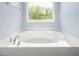 A luxurious soaking tub with chrome fixtures beneath a sunlit window at 223 Triumph Dr, Elon, NC 27244