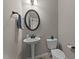 Small powder room featuring a decorative mirror, pedestal sink, toilet, and towel rack at 24 Kaki Ct, Selma, NC 27576