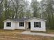 Inviting white home with dark shutters and trim, complemented by a tidy gravel path and surrounding trees at 25 Beechnut Ct, Franklinton, NC 27525
