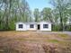 Charming single-story home with white siding and black trim, set against a backdrop of lush trees at 25 Beechnut Ct, Franklinton, NC 27525