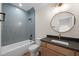 Stylish bathroom featuring blue tiled shower and granite vanity with circular mirror at 250 Pilot Ridge Rd, Zebulon, NC 27597