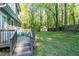View of the back yard featuring a wood deck and spacious, green yard and storage shed at 2700 Ross Rd, Durham, NC 27703
