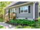 Close-up of the home's entrance, showcasing the wooden staircase, flower bed, and gray siding at 2700 Ross Rd, Durham, NC 27703